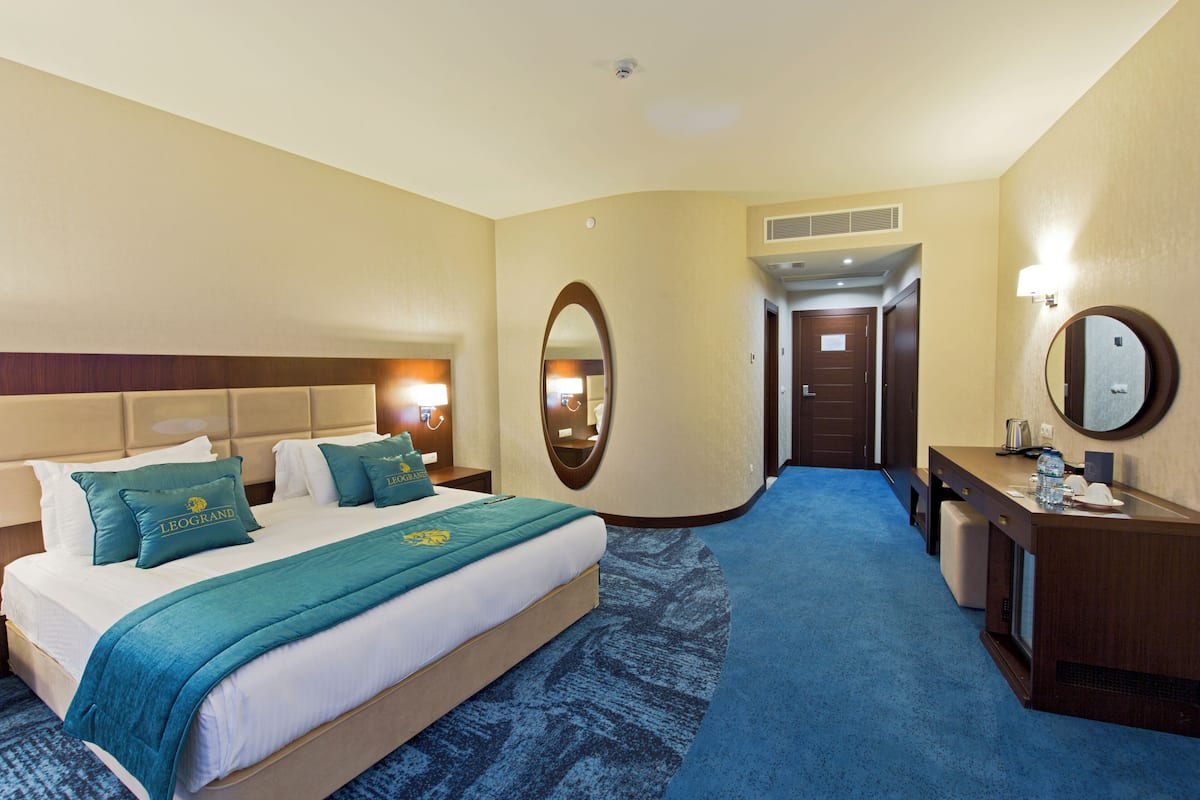 Une chambre d’hôtel comprenant un lit, un bureau, un miroir et une porte donnant sur une autre pièce.