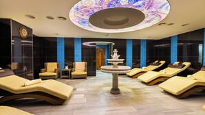 Un spa con varios sillones de sol, una fuente central y un techo decorado.