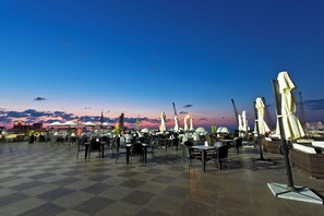 An outdoor café with checkered flooring, tables, chairs, and umbrellas. - JRW Welmond Hotel (Batumi)