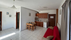 A compact living space with a dining area, kitchenette, and a red sofa. - Imperial Studios (Malevizi)