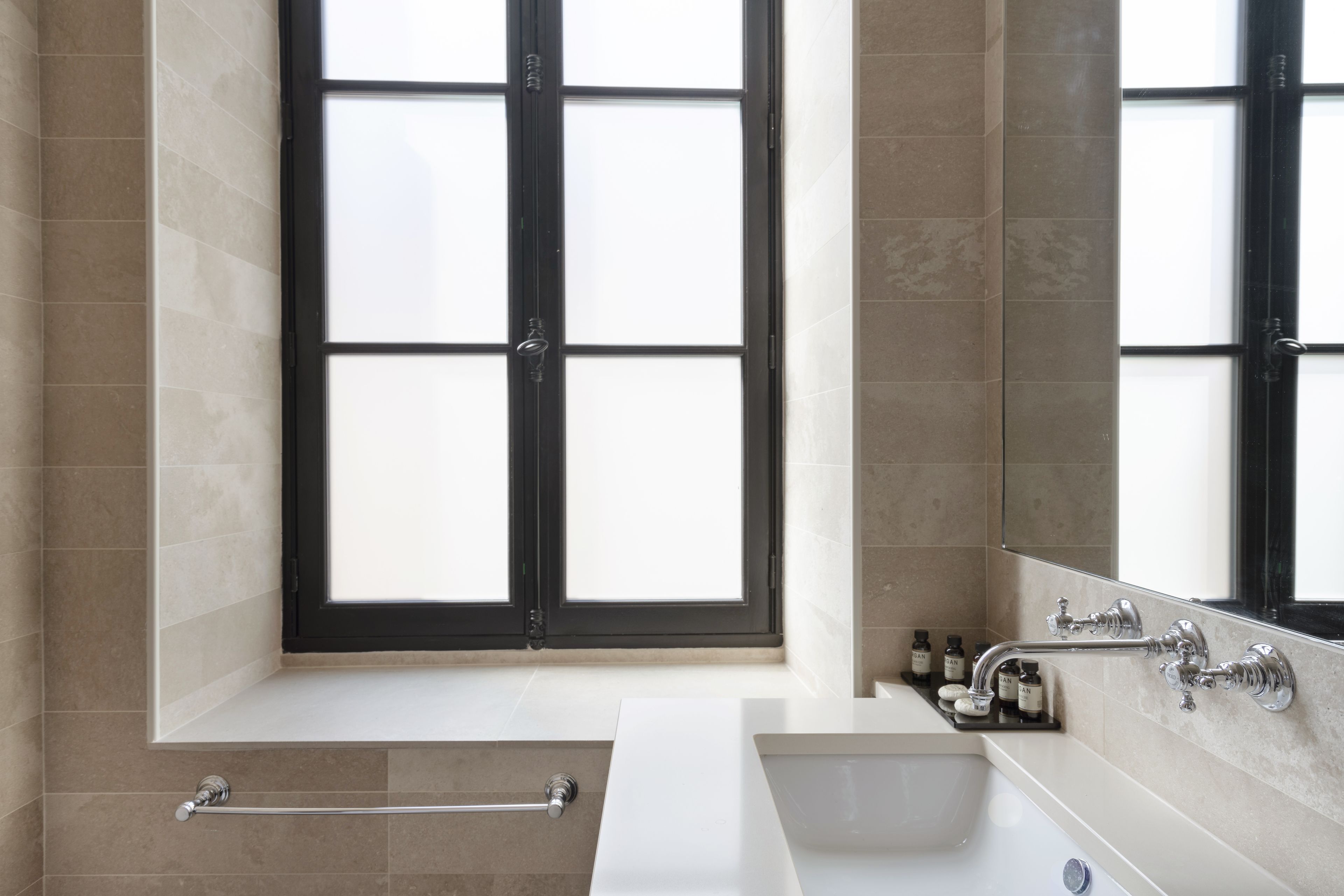 A modern bathroom with a large window, a bathtub, a sink, and a mirror.