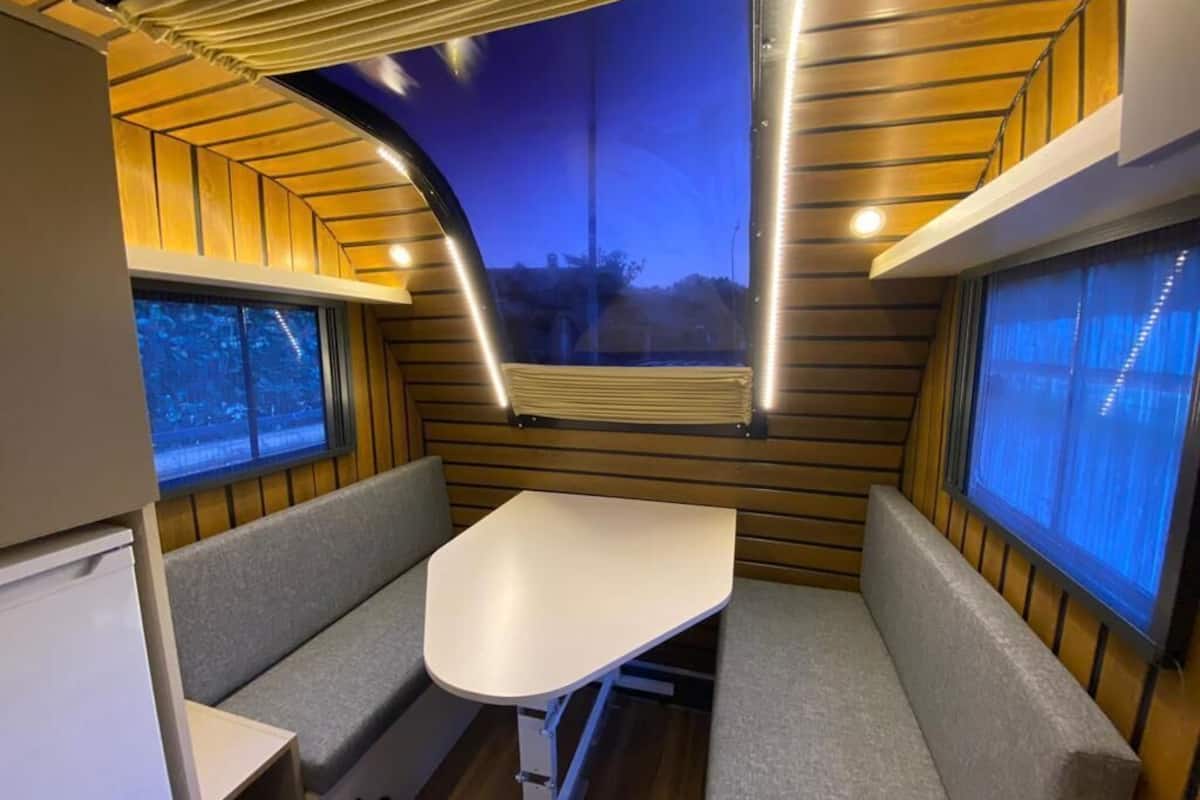 A compact interior with a bench seating area, a table, and a window providing a view of the outside.