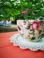 Una maceta con estampado floral sobre una mesa roja y un mantel de encaje.