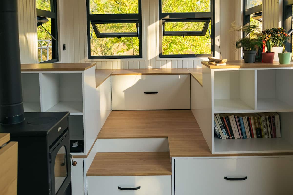 A compact kitchen with built-in appliances, a stove, and a window overlooking greenery.