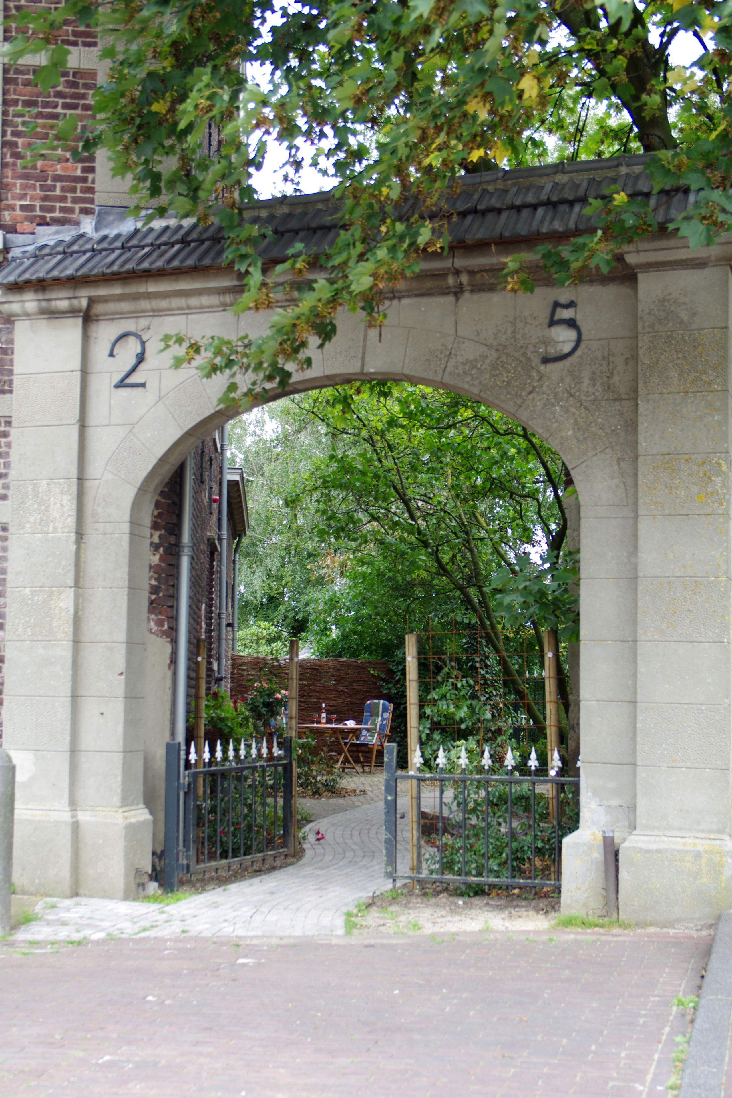 An arched stone gateway with the numbers 2 and 5, leading to a brick building.