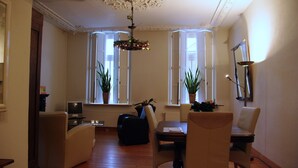 Een woonkamer met een eettafel, stoelen, een televisie en potplanten.