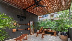 A covered outdoor area with a ceiling fan, wooden benches, a wooden table, and a wall-mounted mirror. - Hotel Era Tulum (Tulum)