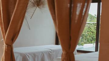 Two beds with crisp white linens, a decorative wall piece, and a view of lush greenery outside.