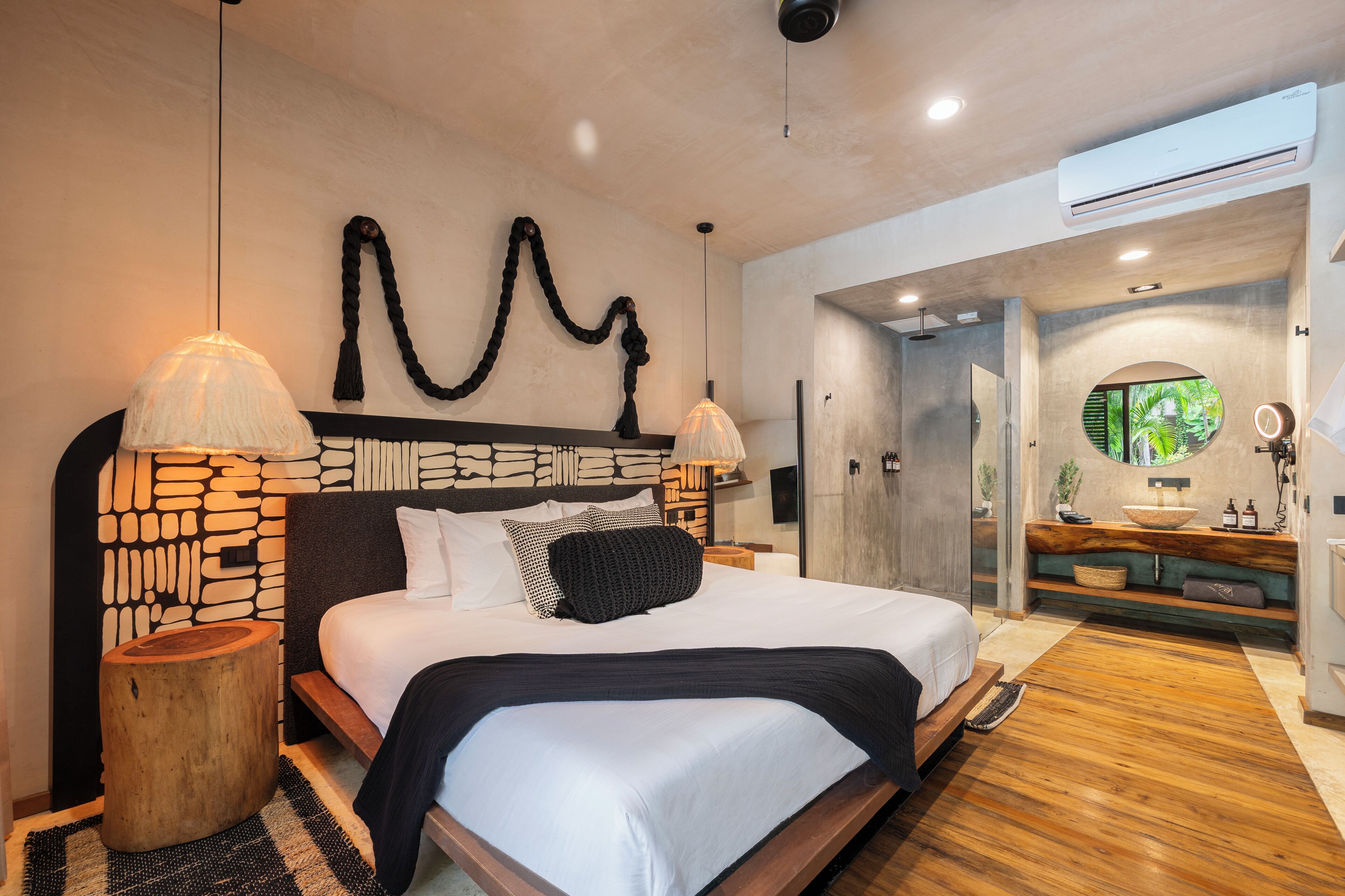 A modern bedroom with a stone-patterned headboard, a large bed with white bedding, two bedside lamps, and a wooden nightstand.