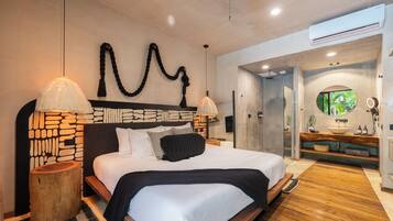 Un dormitorio moderno con cabecera de patrón de piedra, una cama grande con ropa de cama blanca, dos lámparas de noche y una mesita de noche de madera.