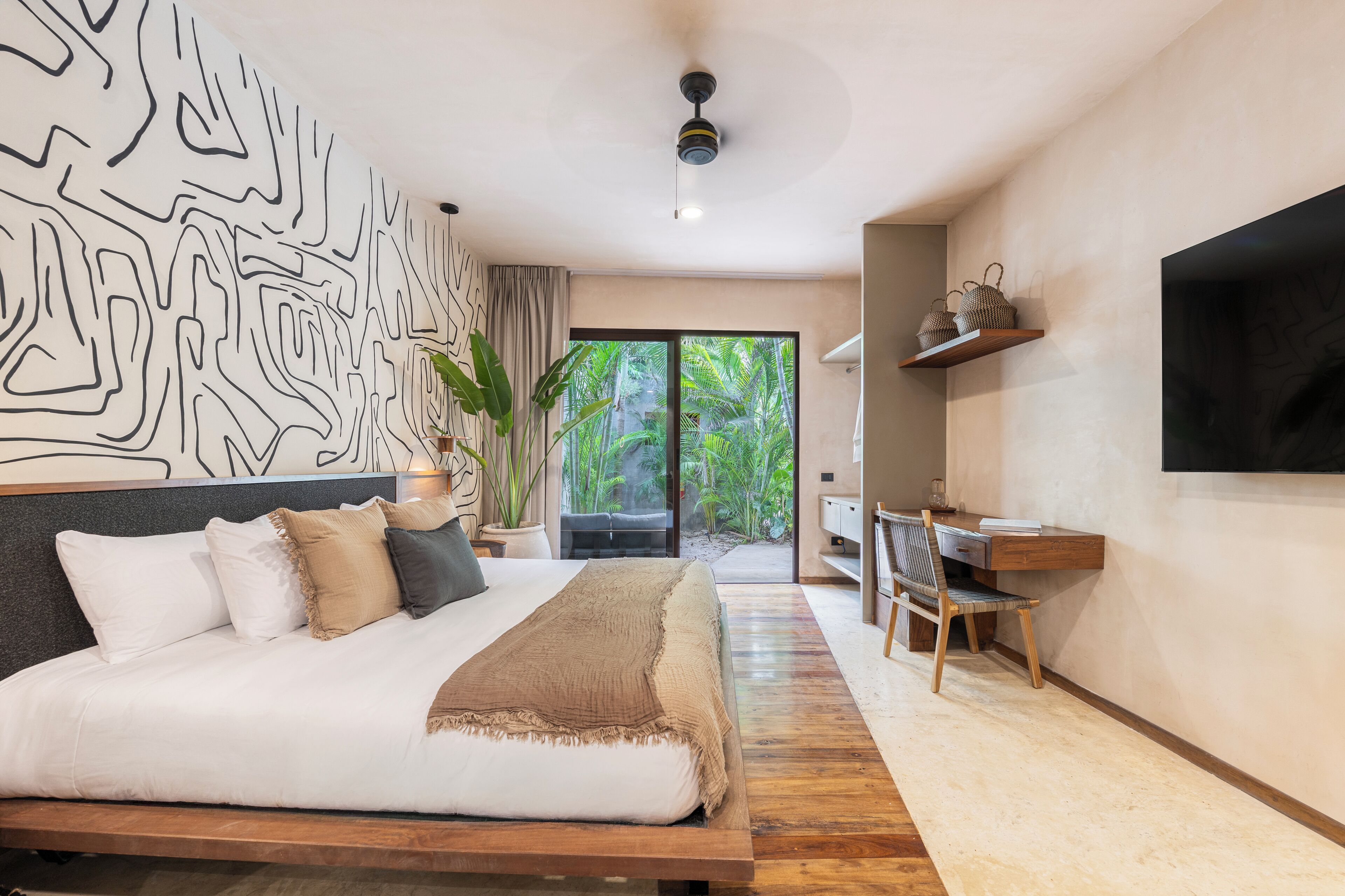 Un dormitorio moderno con una cama grande, un escritorio y un televisor.