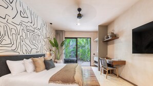 A modern bedroom with a large bed, a desk, and a TV. - Hotel Era Tulum (Tulum)