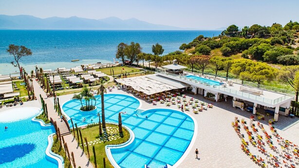 Um resort com uma piscina grande, área de estar ao ar livre e vista para o mar.