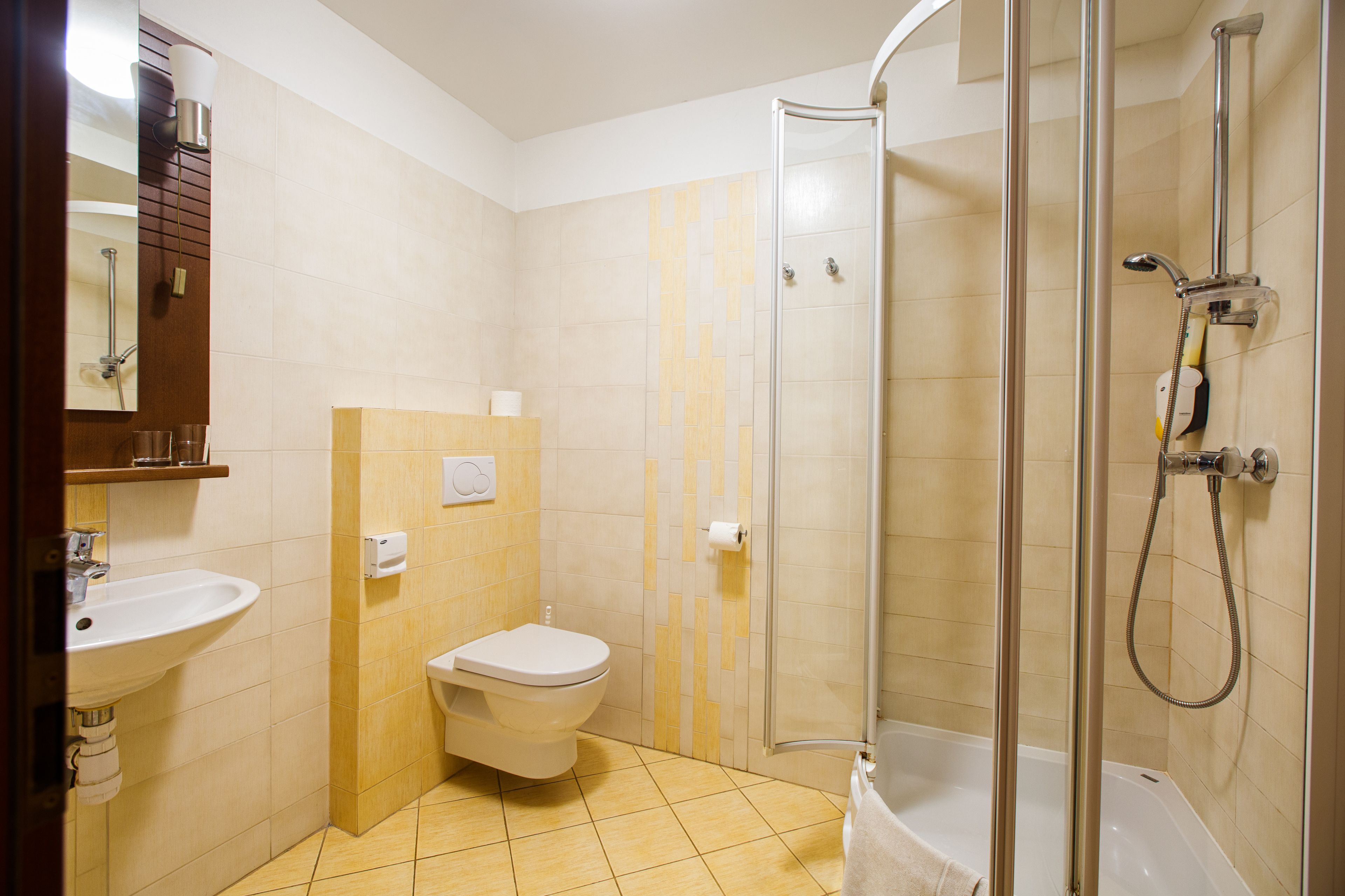 Une salle de bain comprenant des toilettes, un lavabo, une douche et une cabine de douche en verre.