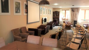 A spacious room with multiple seating areas, including leather sofas and chairs, arranged around a central table. - Apartmány Mlynky (Mlynky)