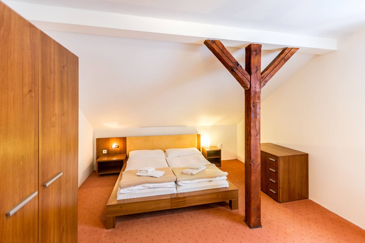 A bedroom with a wooden bed, wooden wardrobe, and a nightstand with a lamp.