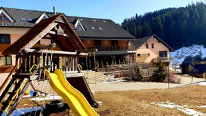 A chalet-style building with a wooden deck and a yellow slide. - Apartmány Mlynky (Mlynky)