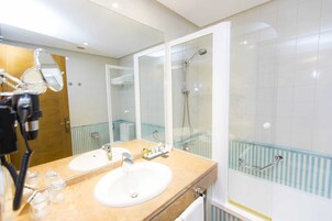 Un baño con dos lavamanos, ducha y cabina de ducha con paredes de vidrio.