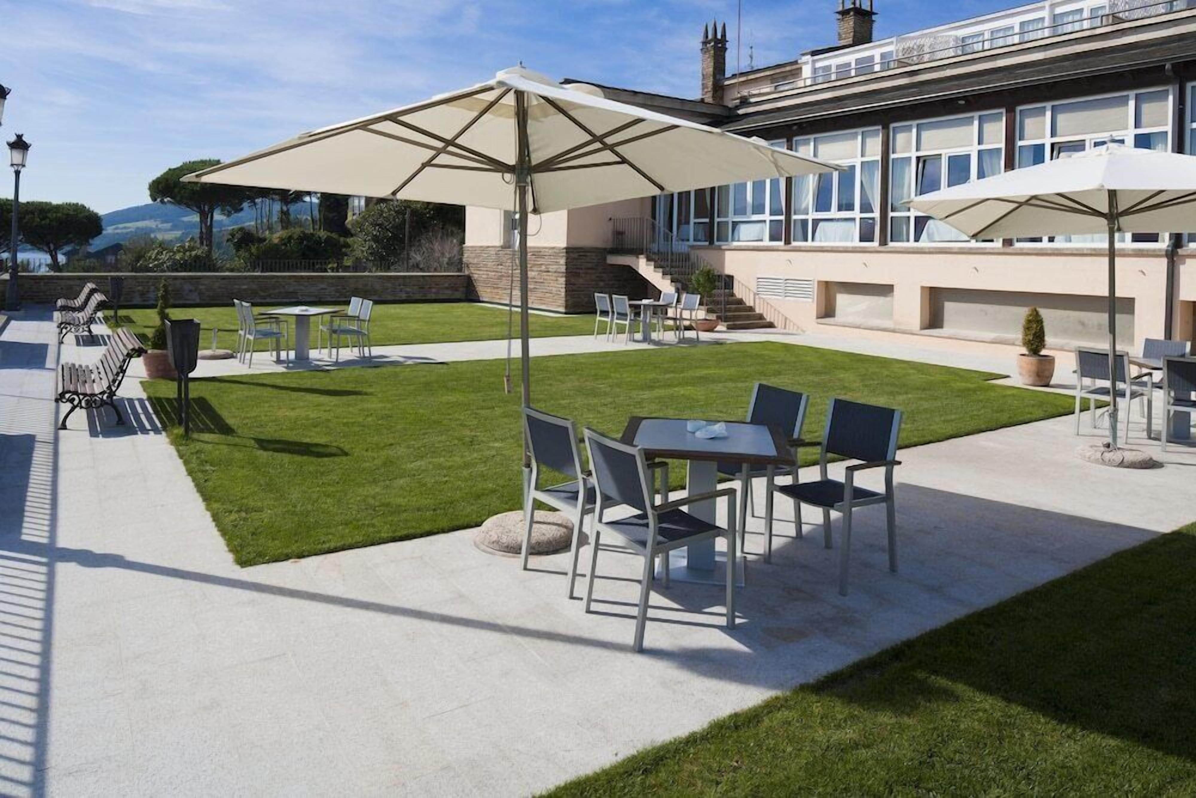 Een terras met buitenmeubilair, inclusief tafels en stoelen, en parasols voor schaduw.
