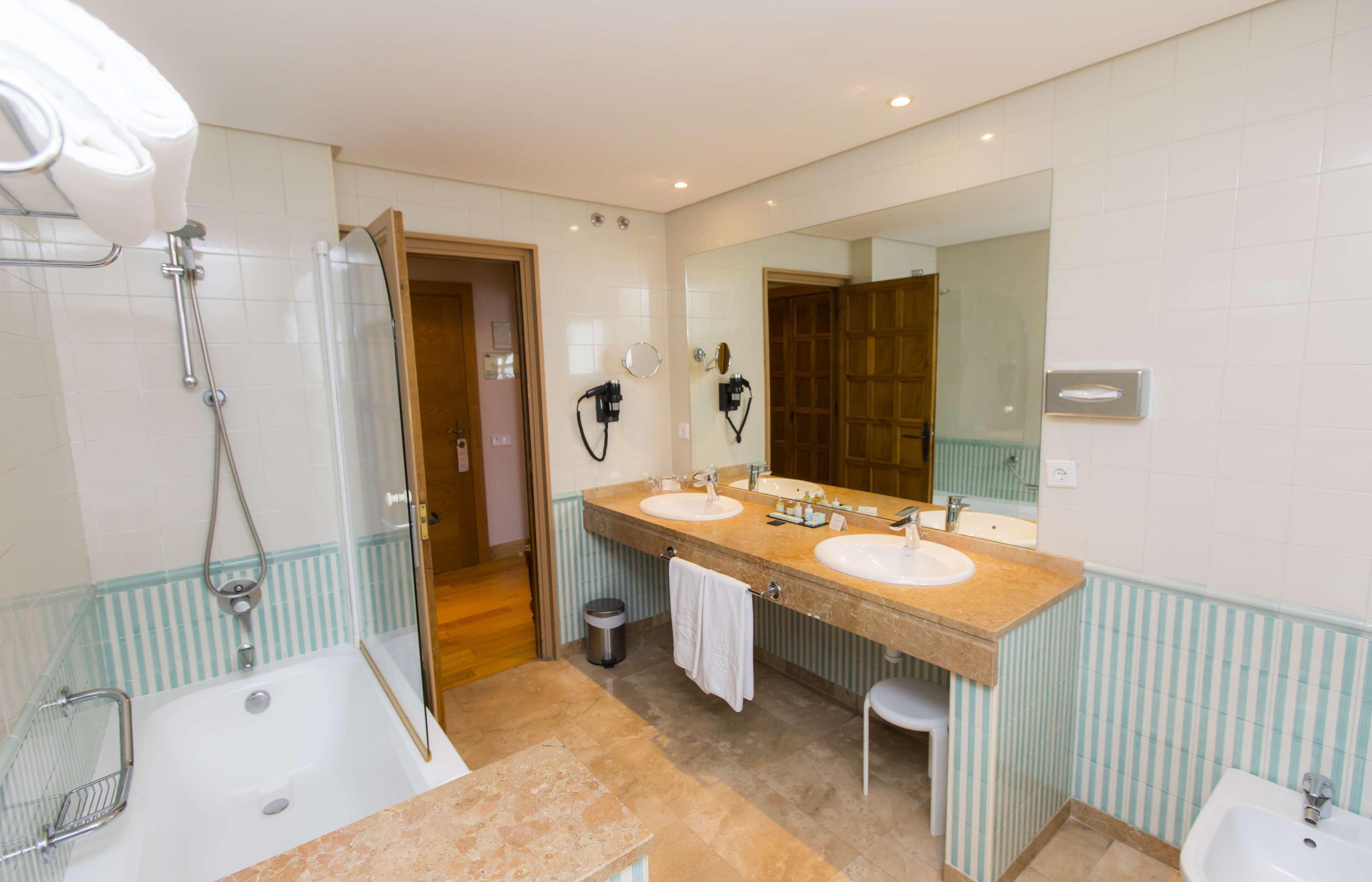 A bathroom with a bathtub, two sinks, a large mirror, and a shower.