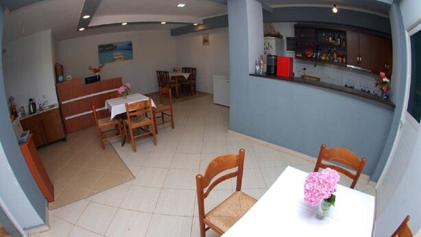 Un coin repas avec une table dressée pour deux personnes, une cuisine avec un bar et un petit réfrigérateur.