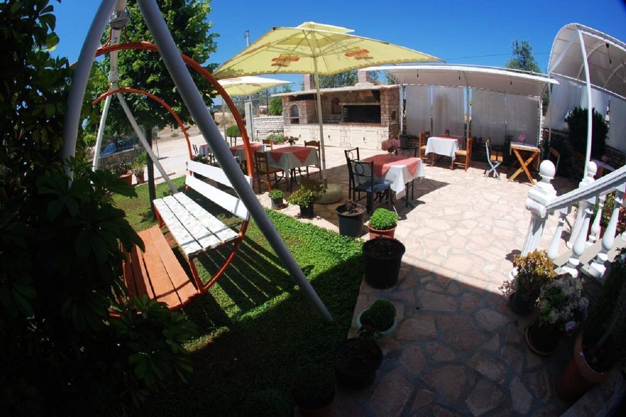 An outdoor patio area with a swing set, tables, chairs, and a barbecue grill.