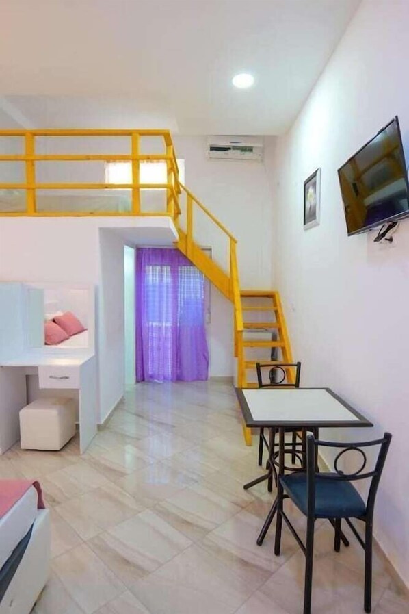 A compact living space with a loft bedroom, a dining area, and a staircase.