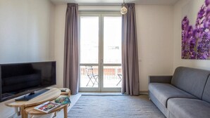 A living room with a flat-screen TV, a sofa, a coffee table, and a large window with curtains. - Coco Places (Florence)