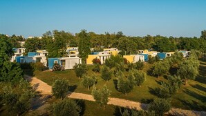 A row of mobile homes with a grassy area and trees in the foreground. - Aminess Maravea Camping Resort (Novigrad)