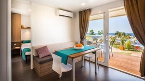 A modern room with a dining table, a sofa, and a view of the sea. - Aminess Maravea Camping Resort (Novigrad)