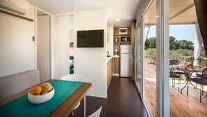 A modern kitchen with a flat-screen TV, a dining area with a table and chairs, and a balcony with outdoor seating. - Aminess Maravea Camping Resort (Novigrad)