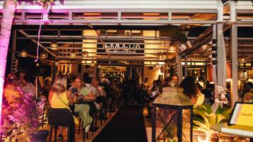 An outdoor dining area with a black carpet leading to a restaurant named "EMILEDA Seafood & Bar".