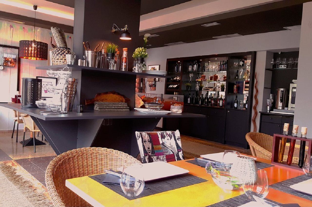A modern bar area with a central island, bar stools, and shelves stocked with bottles.