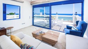 A modern living room with a large sliding glass door leading to a balcony with a view of the sea. - Villa Azure (Kefalonia)
