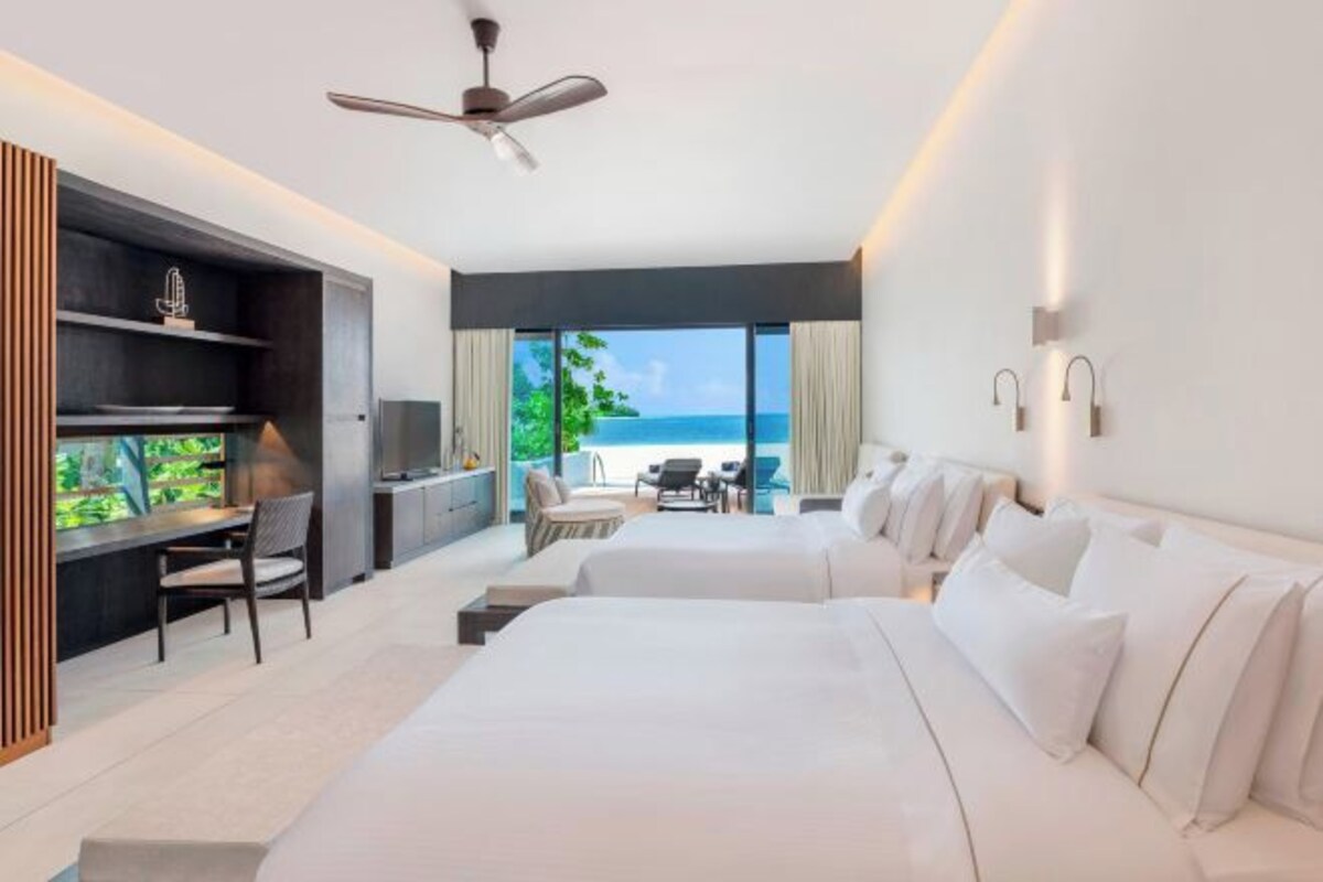 A modern hotel room with a large bed, a desk, and a view of the ocean.
