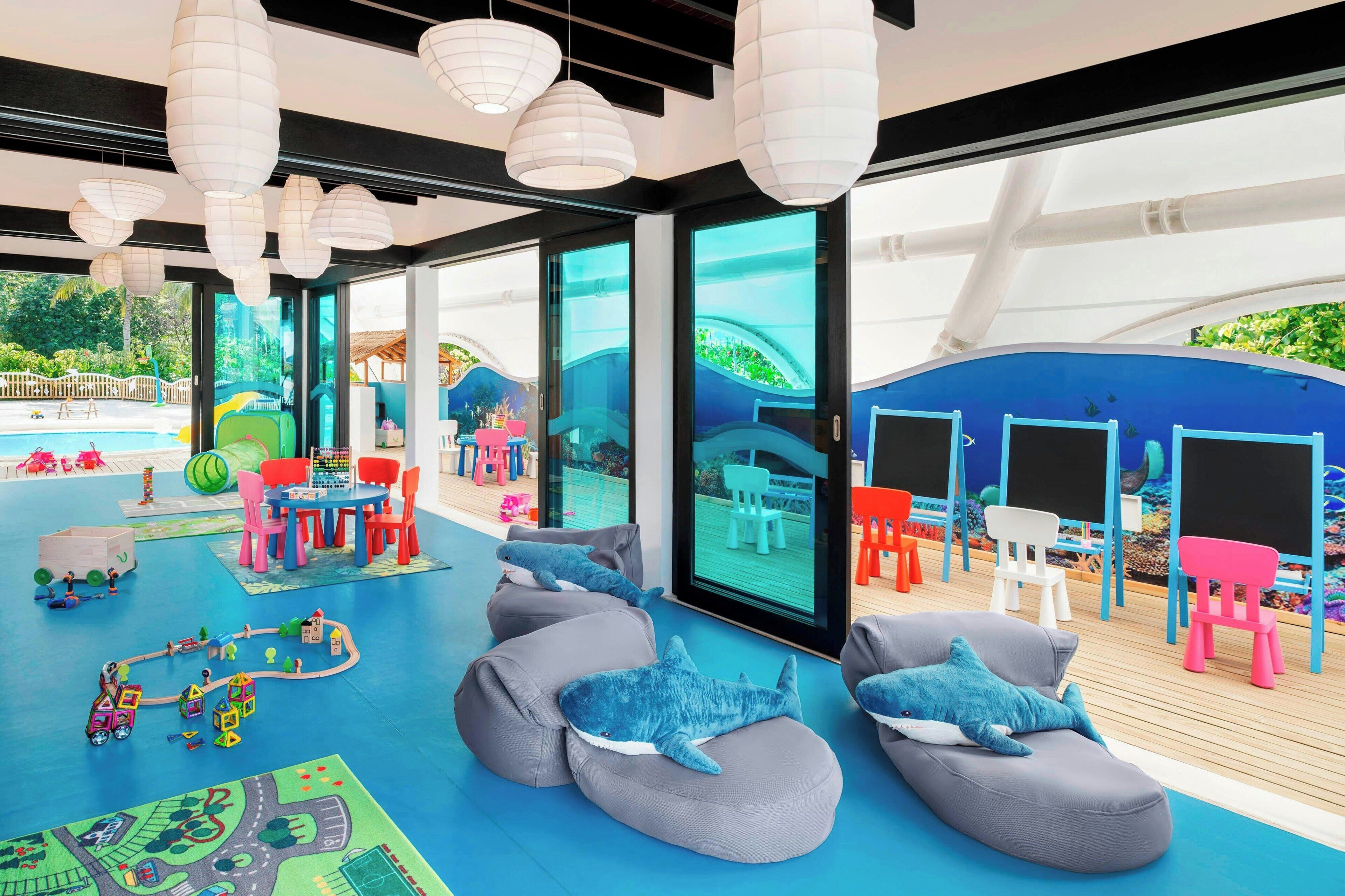 A children's play area with seating, toys, and a view of the pool.