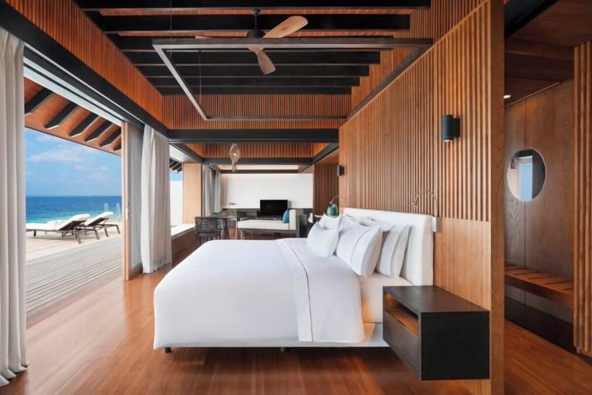 Una habitación de hotel moderna con una cama grande, un escritorio y vista al océano.