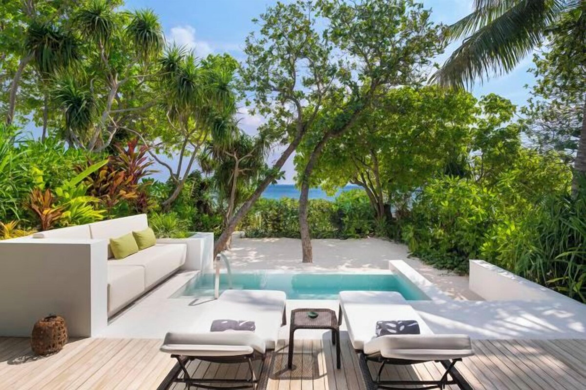 Un espace piscine avec des chaises longues, un canapé blanc et une terrasse en bois.