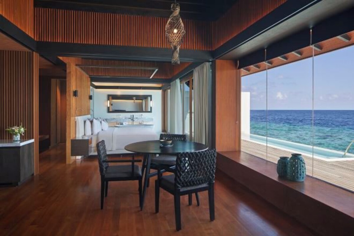 A modern interior with a dining area, kitchen, and large windows overlooking the ocean.