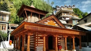 A traditional wooden structure with a checkered floor, surrounded by modern buildings. - Hukam's Holiday Home (Bhuntar)