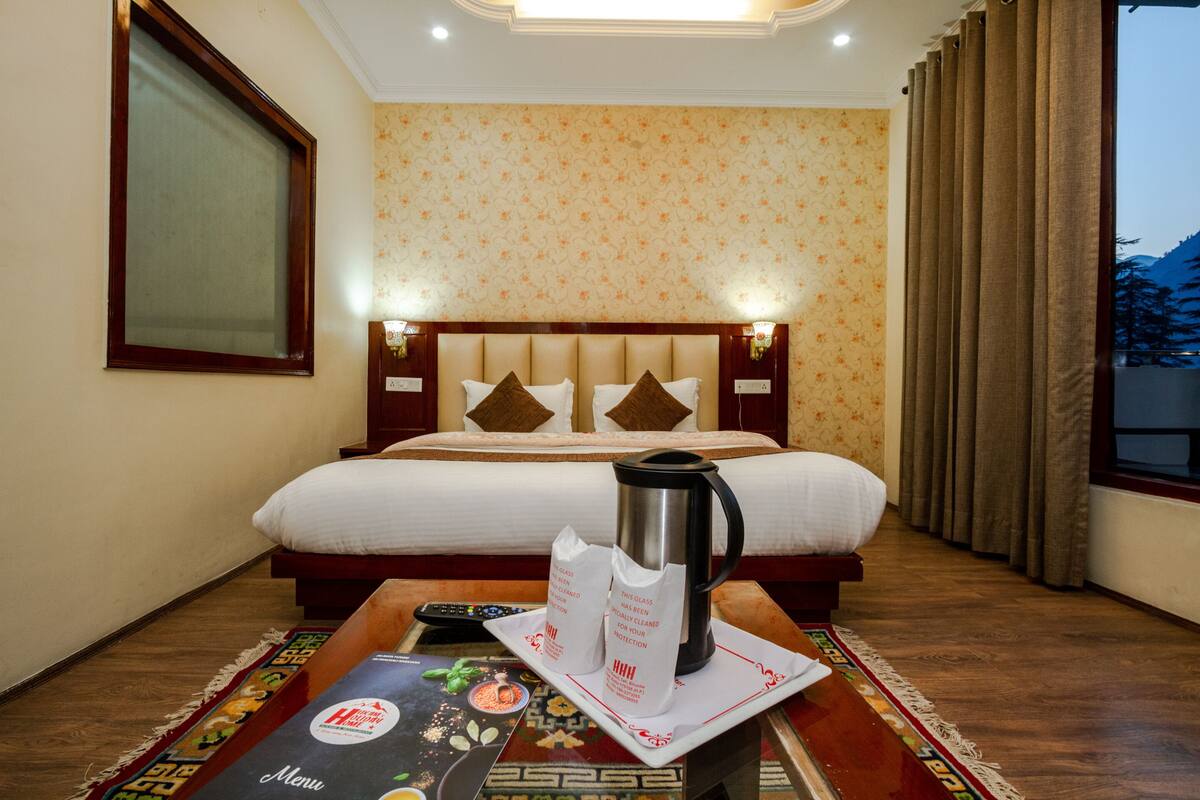 Quarto de hotel com uma cama grande, uma cafeteira e um cardápio sobre a mesa.