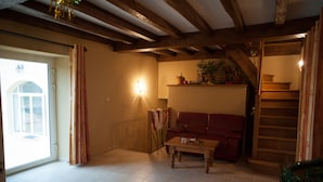 Un salon avec un plafond en bois, un canapé rouge, une table basse en bois et un escalier sur le côté droit.