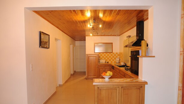 A kitchen with wooden cabinets, a tiled backsplash, and a fruit bowl on the counter. - Spacious countryside house for 8 guests for relaxing holidays in Dordogne region (Sauveterre-la-Lémance)