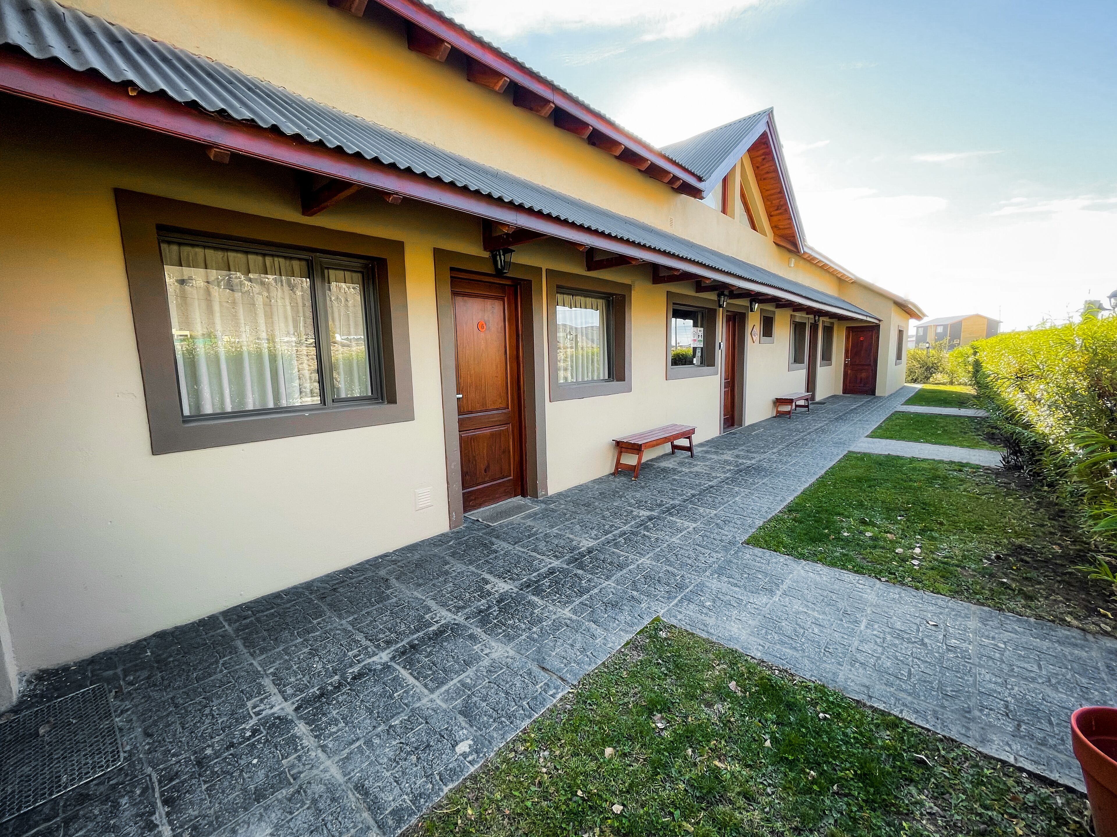 A row of single-story buildings with a tiled walkway and benches.