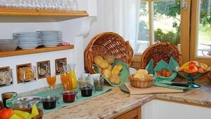 Una encimera de cocina con alimentos para el desayuno, como pan, bollería y fruta.