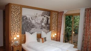 Un dormitorio con una cama grande, dos mesitas de noche con lámparas, un cabecero de madera, un cuadro en la pared y una ventana con cortinas.