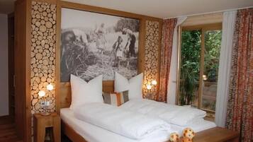 Ein Schlafzimmer mit einem großen Bett, zwei Nachttischen mit Lampen, einem hölzernen Kopfteil, einem Wandbild und einem Fenster mit Vorhängen.