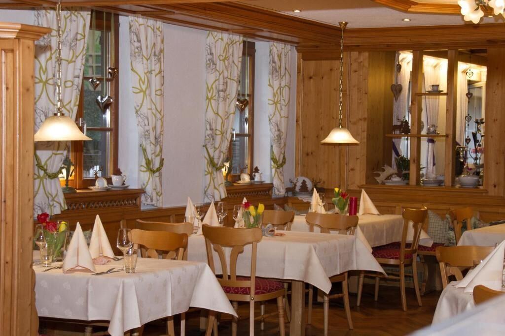 Une salle à manger avec des boiseries, des nappes blanches et des lustres.
