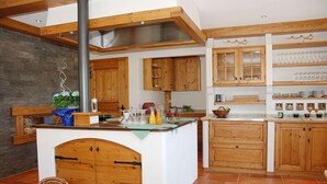 Una cocina con armarios de madera, una isla central y una lámpara colgante.