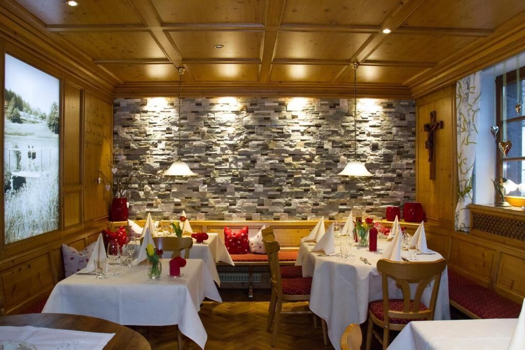 A restaurant with stone walls, wooden ceiling, and tables set for dining.